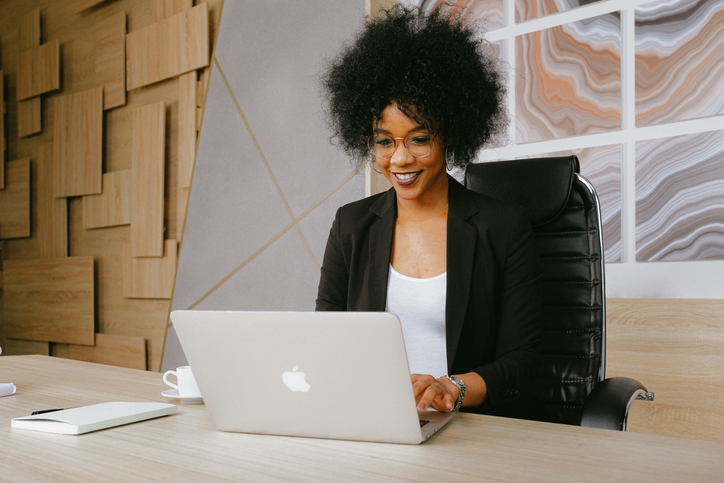 woman-in-black-blazer-sitting-by-the-table-while-using-a-laptop