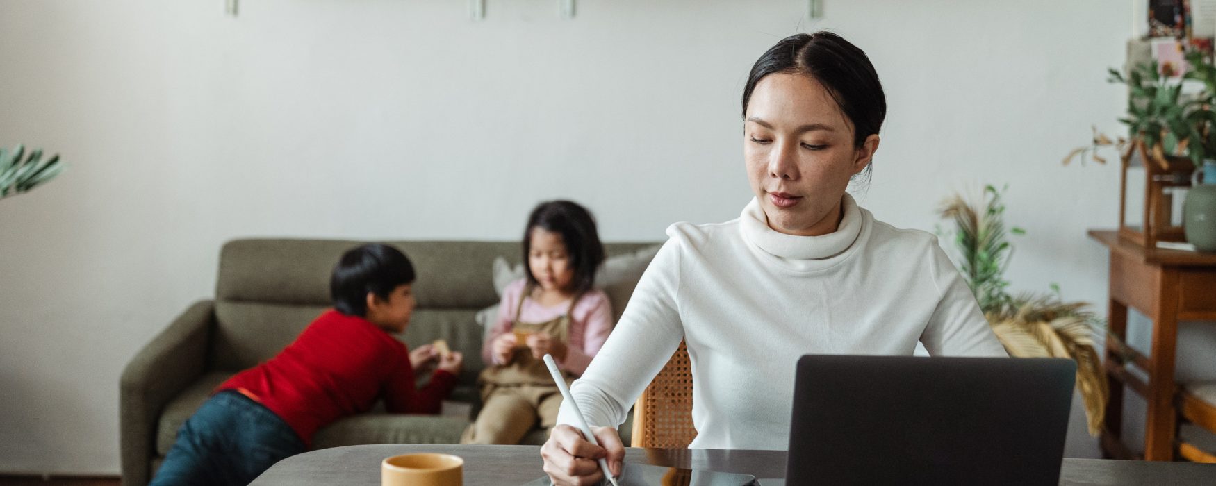 Woman working remotely with children in background