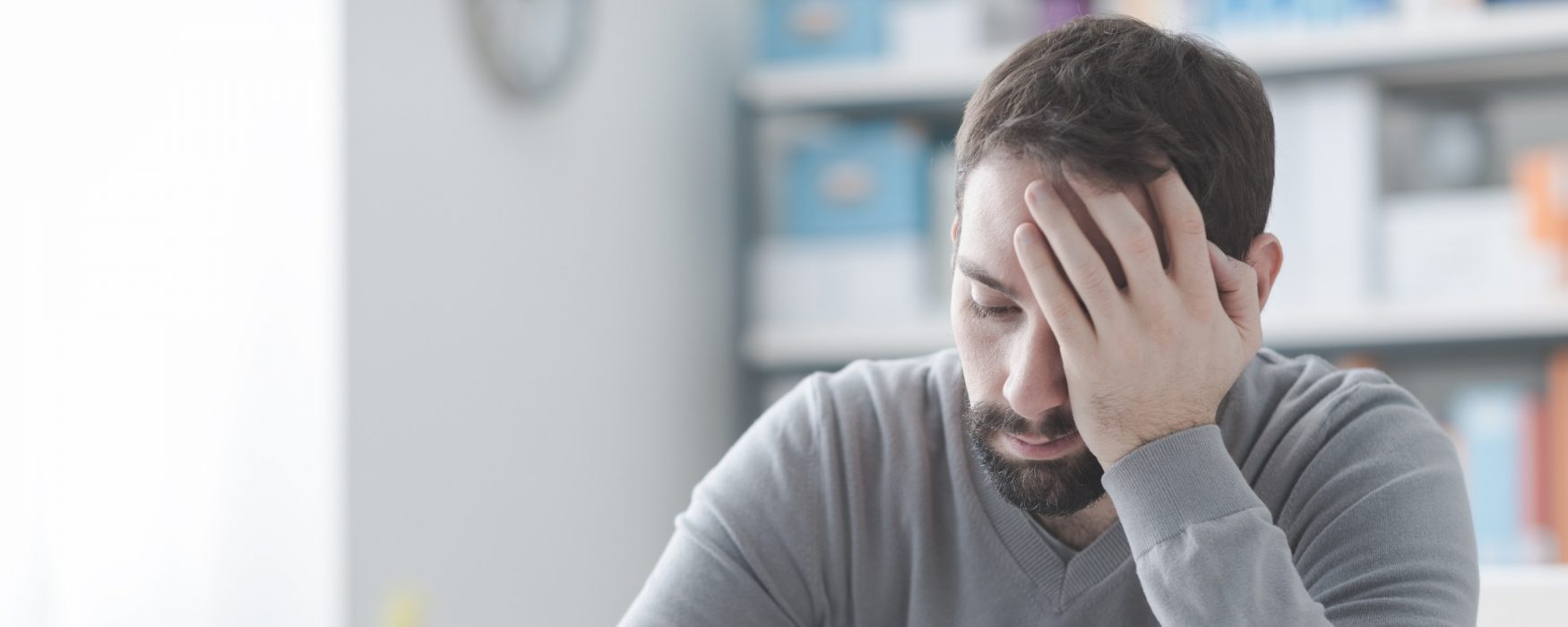 Image of man holding his head in his hand, exhausted