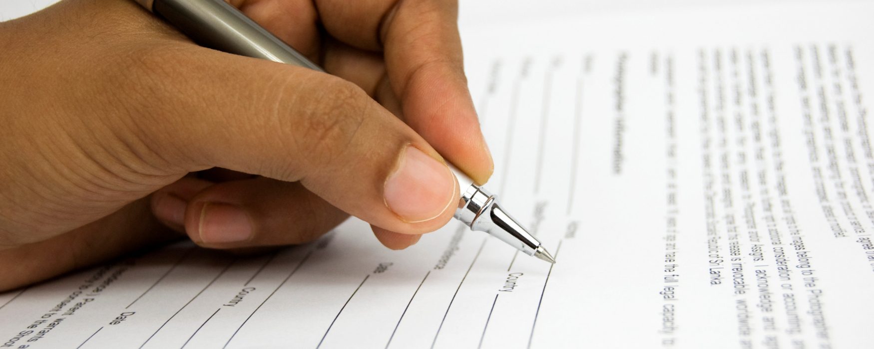 Hand holding a pen, filling out a form