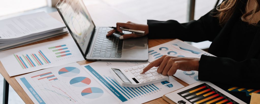 Image of person typing while reviewing various charts and graphs