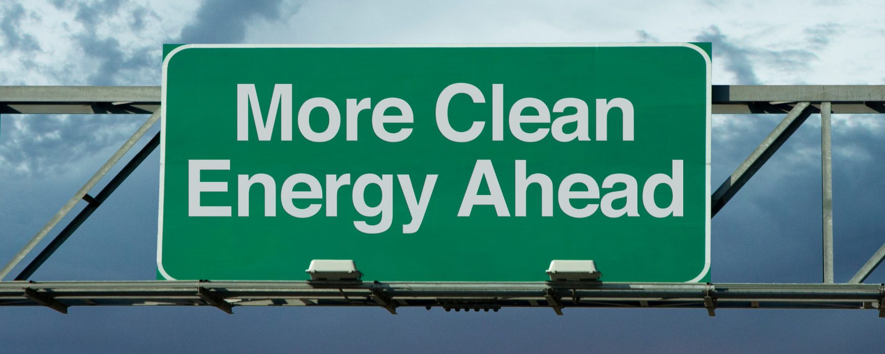 Image of an overhead road sign with the words "More Clean Energy Ahead" printed on it