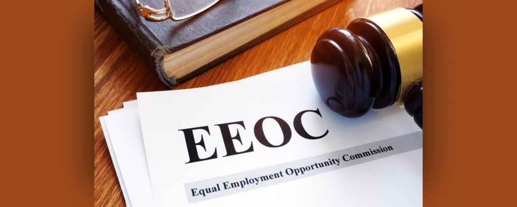 Image of the acronym EEOC printed and set on a table under a gavel