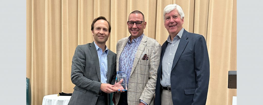 Three men stand next to each other: Brian Calley, Paul Santoro and Rick Snyder. Paul is holding an award.