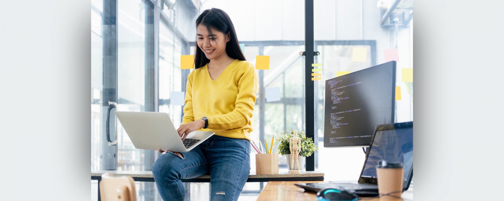 Image of an employee sitting on a desk with a laptop on their lap