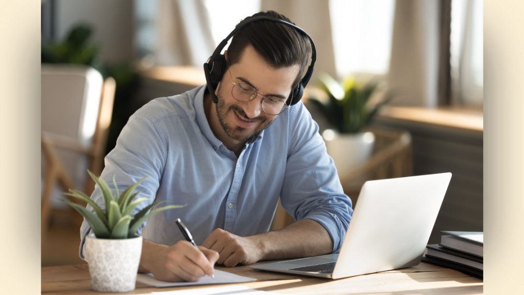 Image of an employee wearing headphones while taking notes