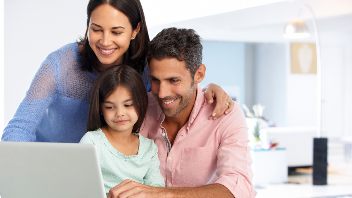 Image of a smiling family working together at a laptop