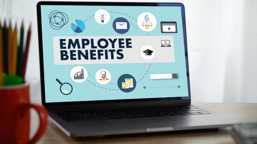 An open laptop displaying "employee benefits" on its screen