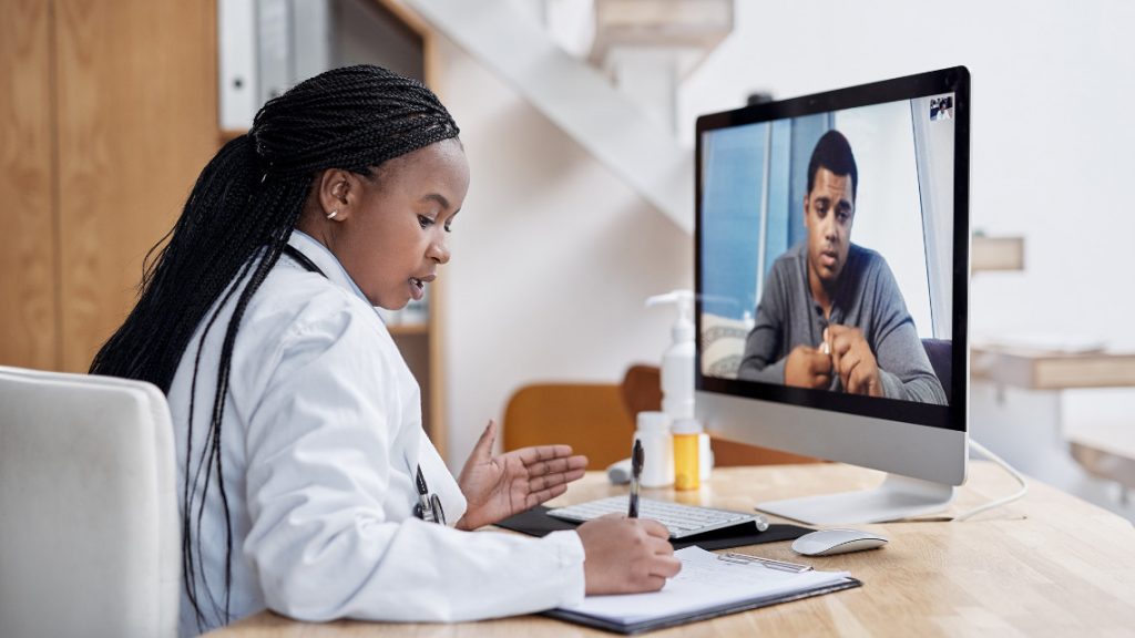 A doctor visits with a patient via computer.