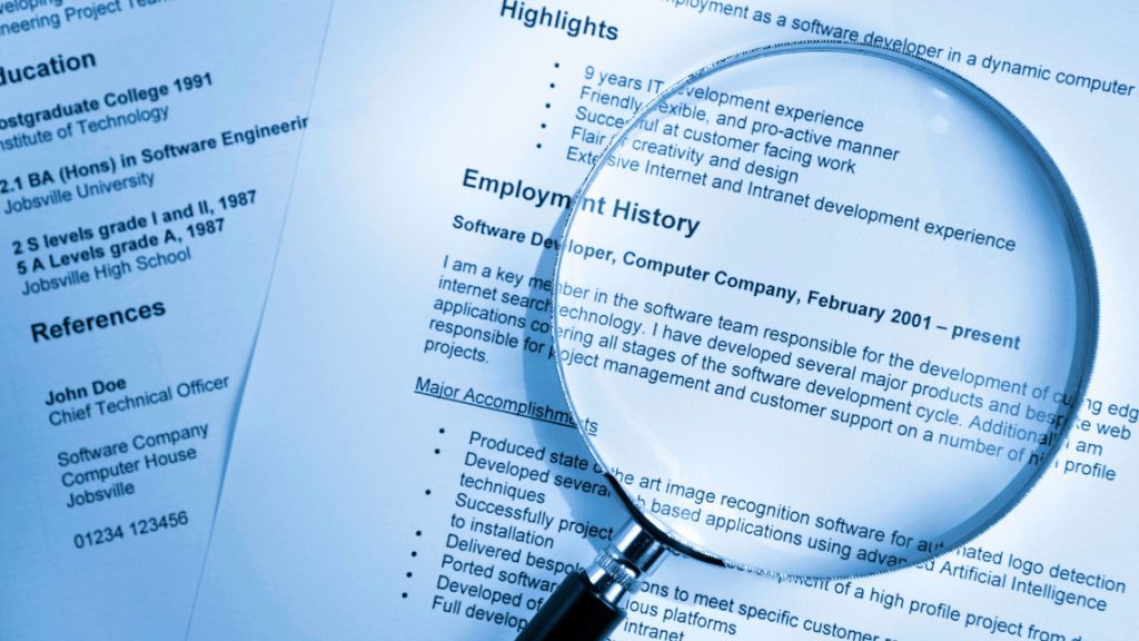 Magnifying glass resting on top of resumes