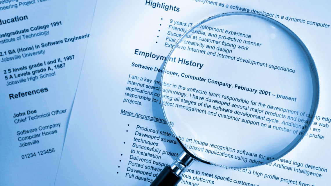 Magnifying glass resting on top of resumes