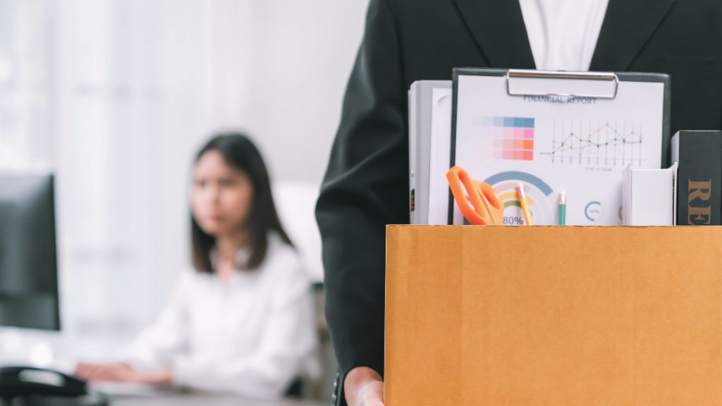 Image representing employee turnover; person carrying a box of items out of an office