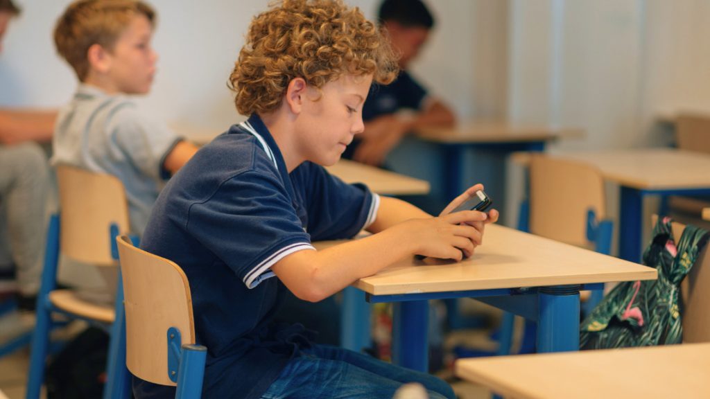 student with a cell phone in a classroom