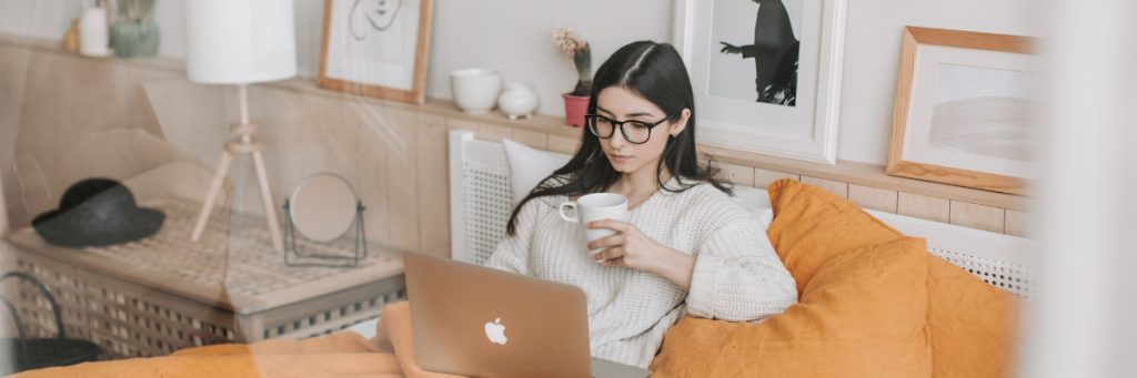 A woman sits on her couch watching a webinar